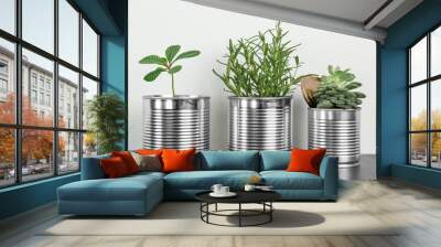 Aluminum cans used as containers for growing plants on wooden table against light background Wall mural