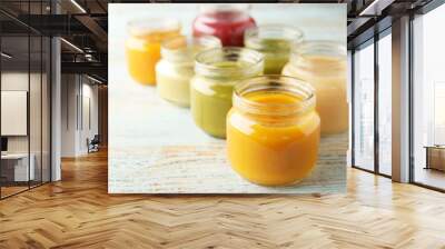 Assortment of jars with tasty baby food on wooden table Wall mural