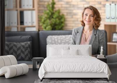 Attractive female psychologist sitting in armchair at office Wall mural