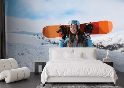 Beautiful female snowboarder on ski piste at snowy resort. Winter vacation Wall mural