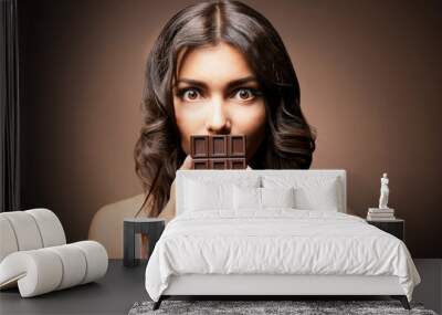 Beautiful girl with chocolate on brown background Wall mural