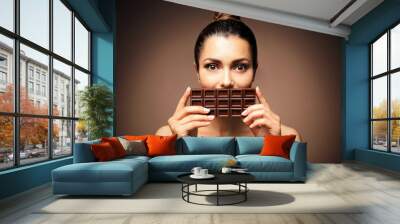 Beautiful girl with chocolate on brown background Wall mural