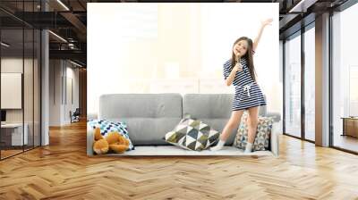 Beautiful little girl singing in a wooden pencil and has fun in the room Wall mural