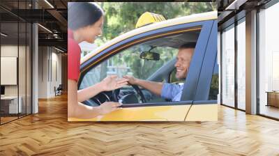 Beautiful woman talking with taxi driver through opened car window Wall mural