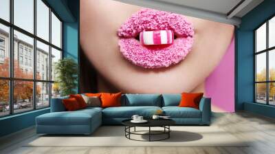 Beautiful young woman holding candy in lips covered with sugar, closeup Wall mural