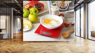 Bowl of raw egg and flour with digital kitchen scales on light wooden table Wall mural