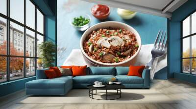 Bowl with tasty brown rice and mushrooms on color wooden table Wall mural