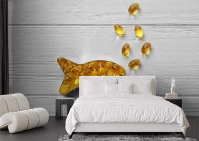 Capsules of cod liver oil arranged in a fish shape on white wooden background Wall mural