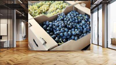 Cardboard box with juicy grapes on market, closeup Wall mural