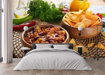 Chili con carne in bowl served with chips on kitchen table Wall mural