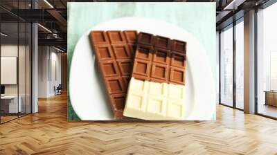 Chocolate bars on plate on wooden background Wall mural