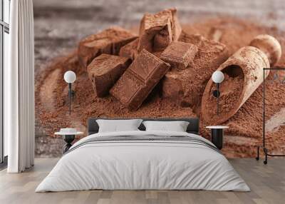 Chopped chocolate chunks, cocoa powder and wooden scoop on table Wall mural