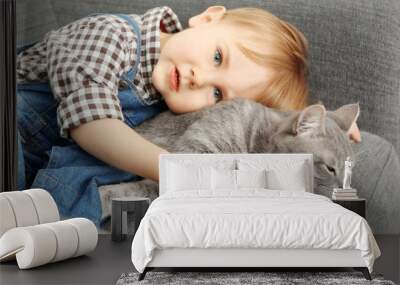 Closeup of adorable little boy with cute cat on grey armchair Wall mural