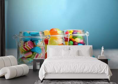 Colorful candies in jars on table on blue background background Wall mural