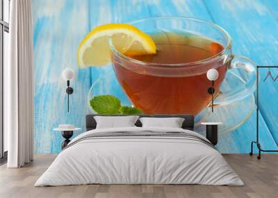 Cup of tea with lemon on table on blue background Wall mural