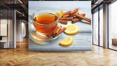 Cup with aromatic hot cinnamon tea and lemon on wooden table Wall mural