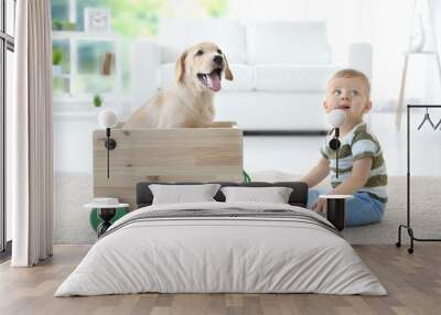 Cute child and Labrador Retriever playing with wooden toy cart at home Wall mural