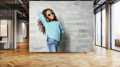 Cute little African American girl with sunglasses against grey wall. Fashion concept Wall mural