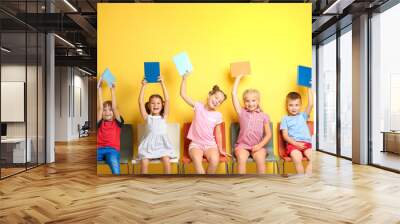 Cute little children with books sitting near color wall Wall mural