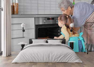 Cute little girl and her grandmother making cookies on kitchen Wall mural