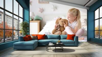 Cute little girl hugging toy bunny on bed at home Wall mural