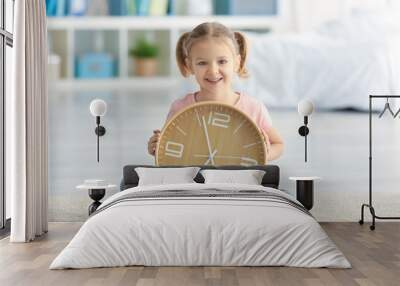 Cute little girl with big clock sitting on floor at home Wall mural