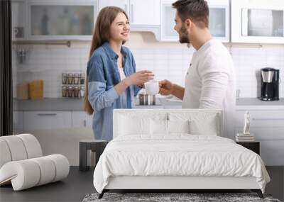 Cute young couple drinking coffee in kitchen Wall mural