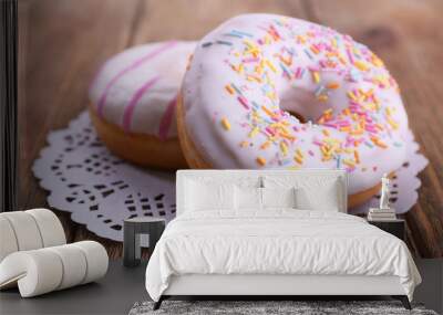 Delicious donuts with icing on lace doily on wooden background Wall mural