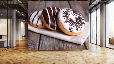 Delicious donuts with icing on napkin on wooden background Wall mural