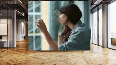 Depressed young woman near window at home Wall mural