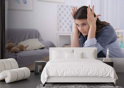 Depressed young woman sitting in armchair at home Wall mural