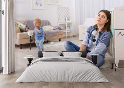 Depressed young woman with cute baby at home Wall mural