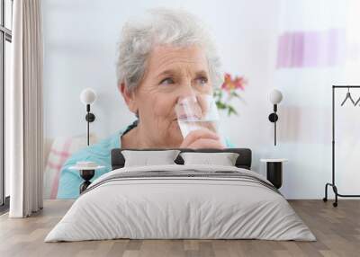 Elderly woman drinking water at home. Concept of retirement Wall mural