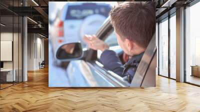 Emotional young man inside car in traffic jam Wall mural