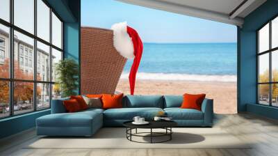 Empty sunbed with Santa hat on beach near sea. Christmas holidays concept Wall mural