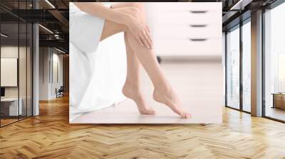 Epilation concept. Young woman sitting on sofa, closeup view of female legs Wall mural