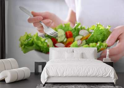 Female hand and bowl of vegetable salad on wooden table closeup Wall mural