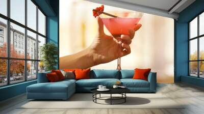 Female hand with glass of cocktail on bar background Wall mural