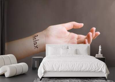 Female hand with tattoo word RELAX on grey background Wall mural