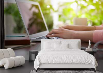 Female hands working with a laptop outdoor on blurred green plant background Wall mural