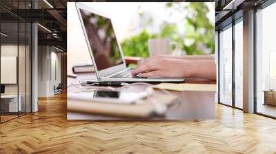 Female hands working with a laptop outdoor on blurred green plant background Wall mural