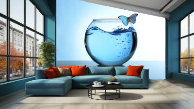 Fish bowl with water and butterfly on it on light blue background Wall mural