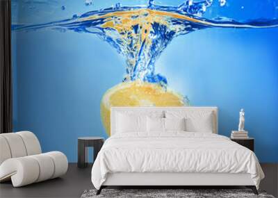 Fresh orange falling in water on blue background Wall mural