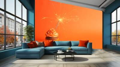 Fresh tasty cupcake with sparkler on orange background Wall mural