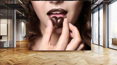 Girl eating chocolate, closeup Wall mural