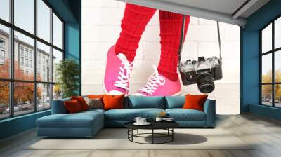 Girl in sneakers with retro photo camera in room Wall mural