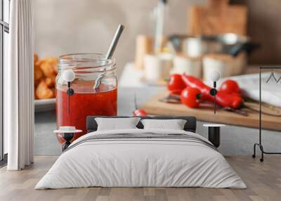 Glass jar with chili sauce on kitchen table Wall mural