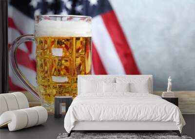 Glass of beer on table against American flag background Wall mural