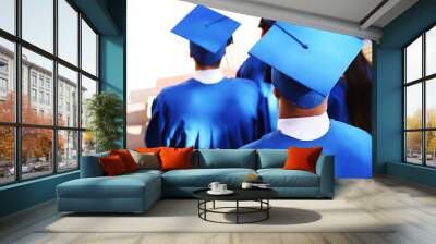 Graduate students wearing graduation hat and gown, outdoors Wall mural