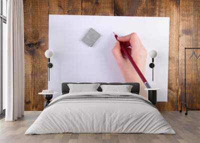 Hand holding pencil and erase with paper on wooden background Wall mural